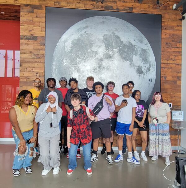 Summer Discovery group of students posing in front of Moon photo at Moonshot Museum