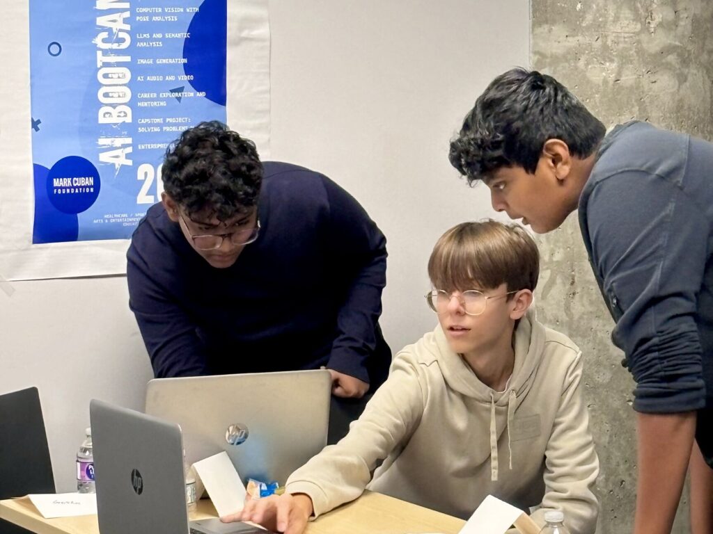 A mentor helps a young boy with an AI project on his laptop.