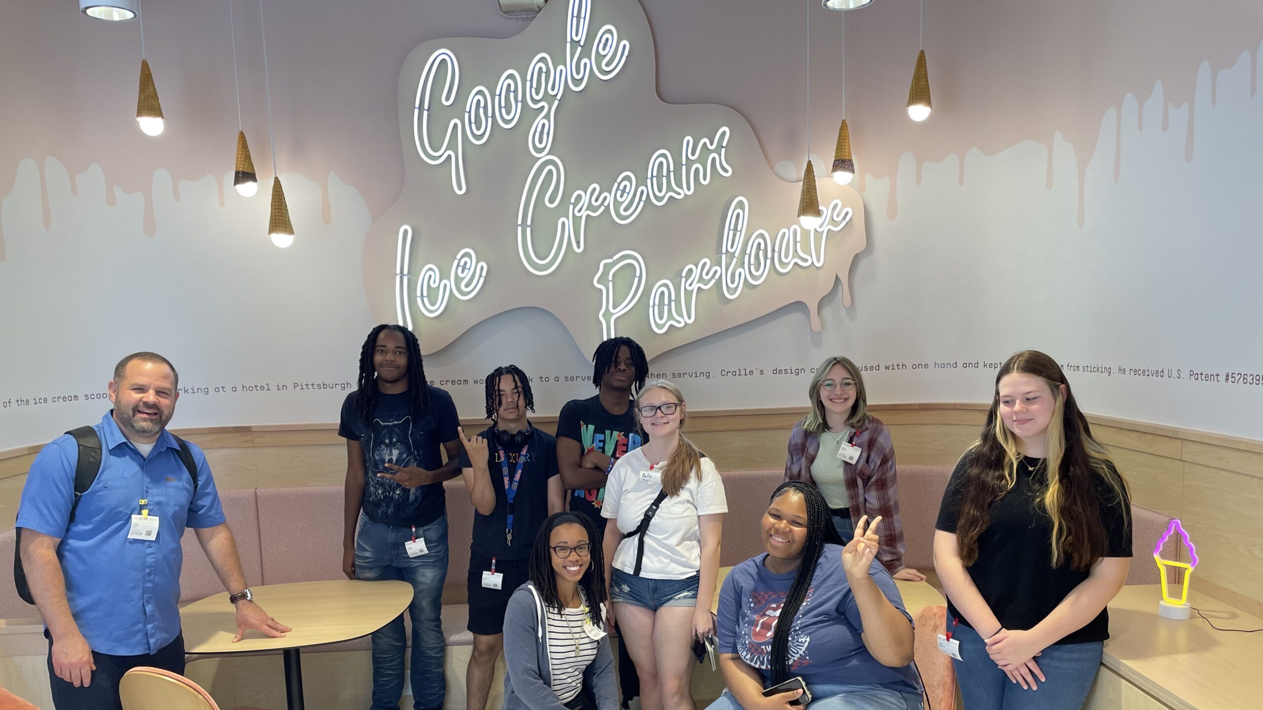 Students in the Summer Program visit Google and pose in front of a neon sign that reads, "Google Ice Cream Parlor"
