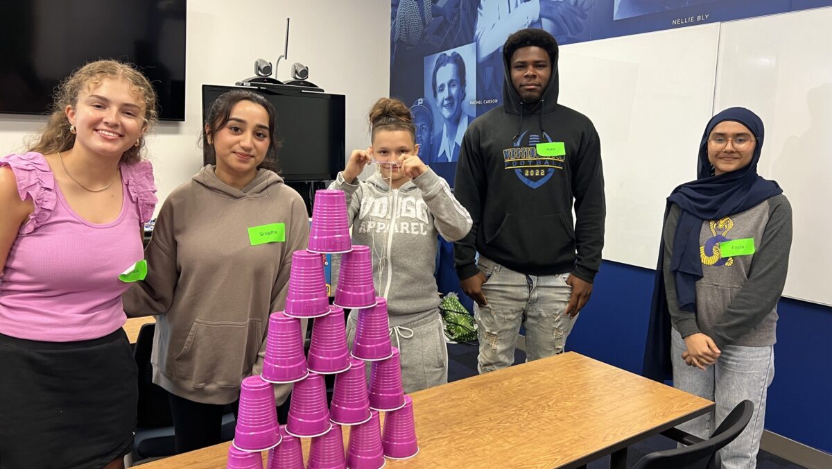 Students pose with stacked solo cups on a table