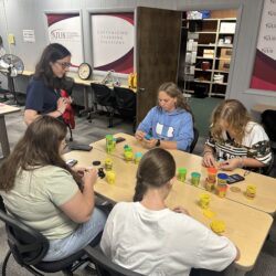 A group of Summer Discovery students sit at a table and make models with Play-Doh