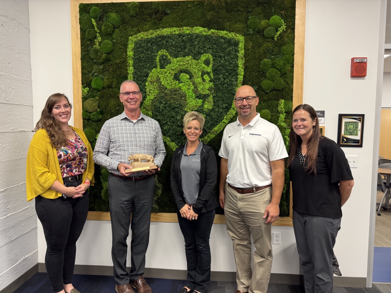 Emma, Tom, Janel, Justin, Tracey with lion award in front of moss wall
