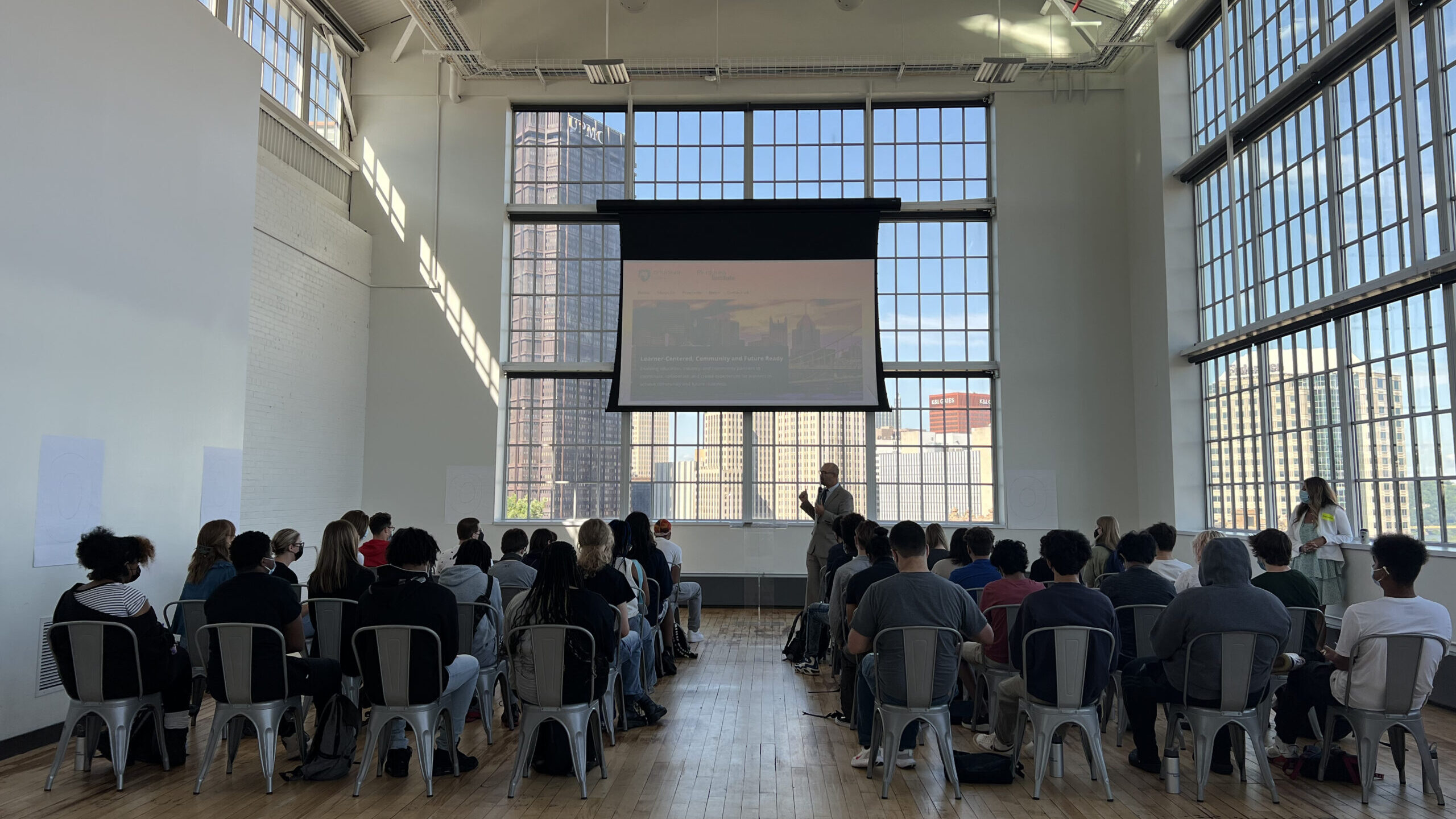 Readiness Institute Summer Program participants watch a slideshow in a room with large windows