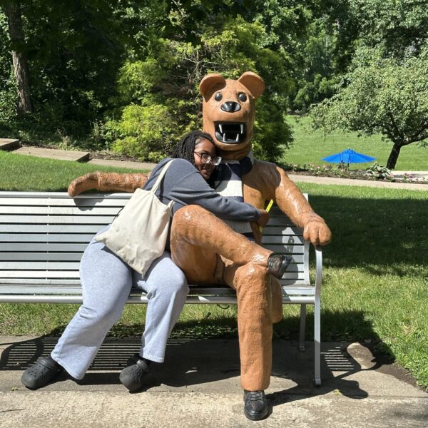 student sitting on bench hugging sitting lion mascot statue at Penn State Greater Allegheny