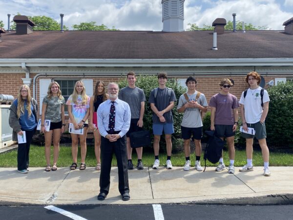 The Summer Program Central PA group poses in front of a low, brick building