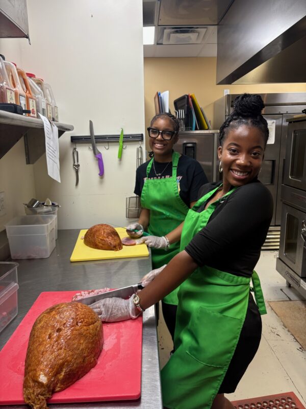 two students smiling while volunteering in kitchen at 412 Food Rescue