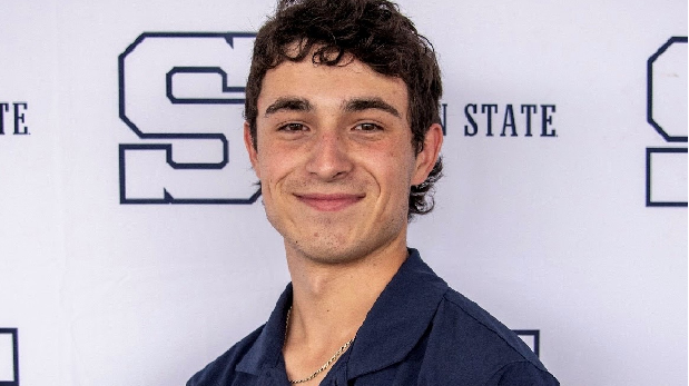 Keagan in blue Penn State polo in front of white Penn State logo backdrop