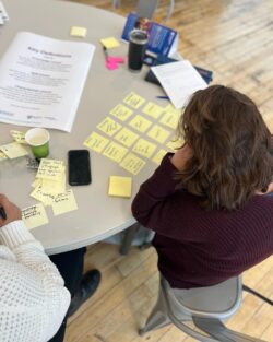 A woman sits at a table and reviews sticky notes