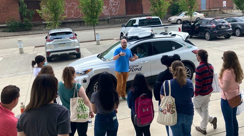 A group of students look at a self-driving vehicle